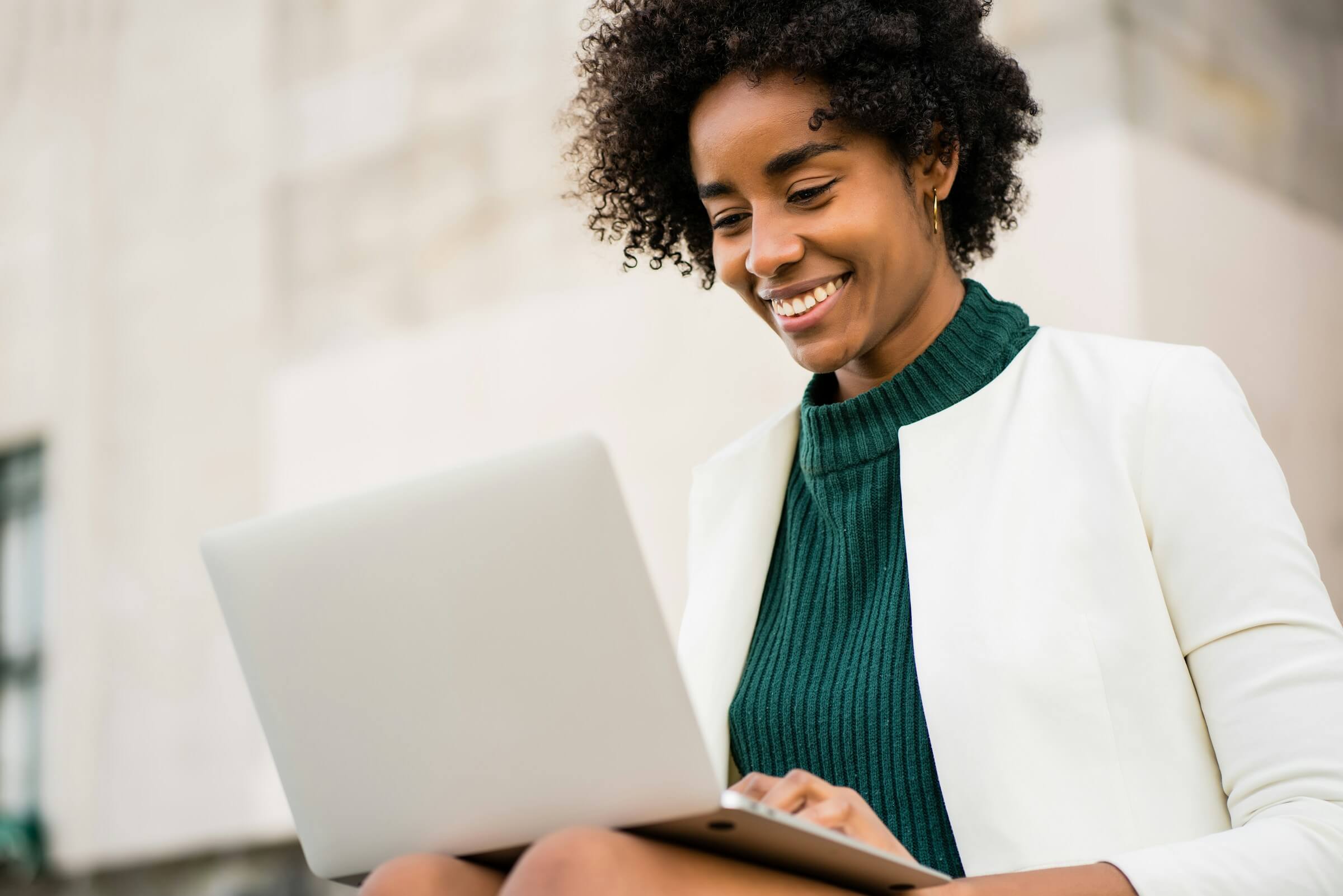 A clinician smiling while working on a laptop